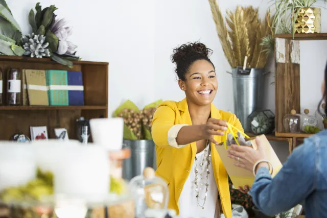 Salesperson in yellow jacket handing over purchase