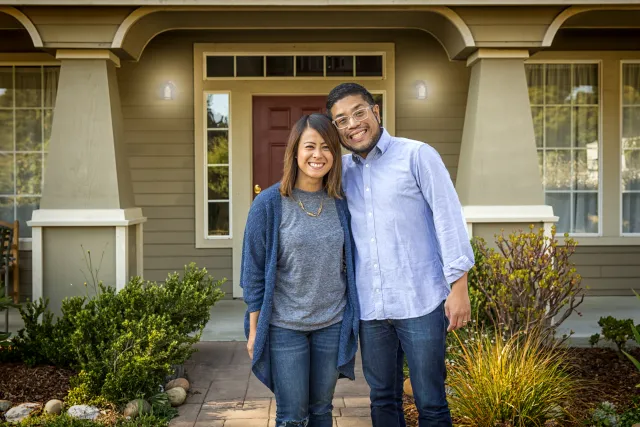 Couple Smiling in front of their home