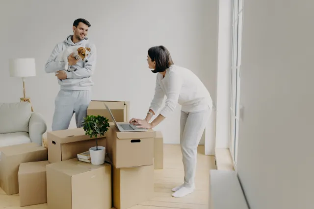 Woman using laptop on top of moving boxes - Extraco Banks