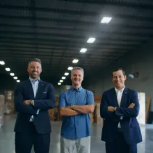 Three men standing next to each other smiling with their arms crossed